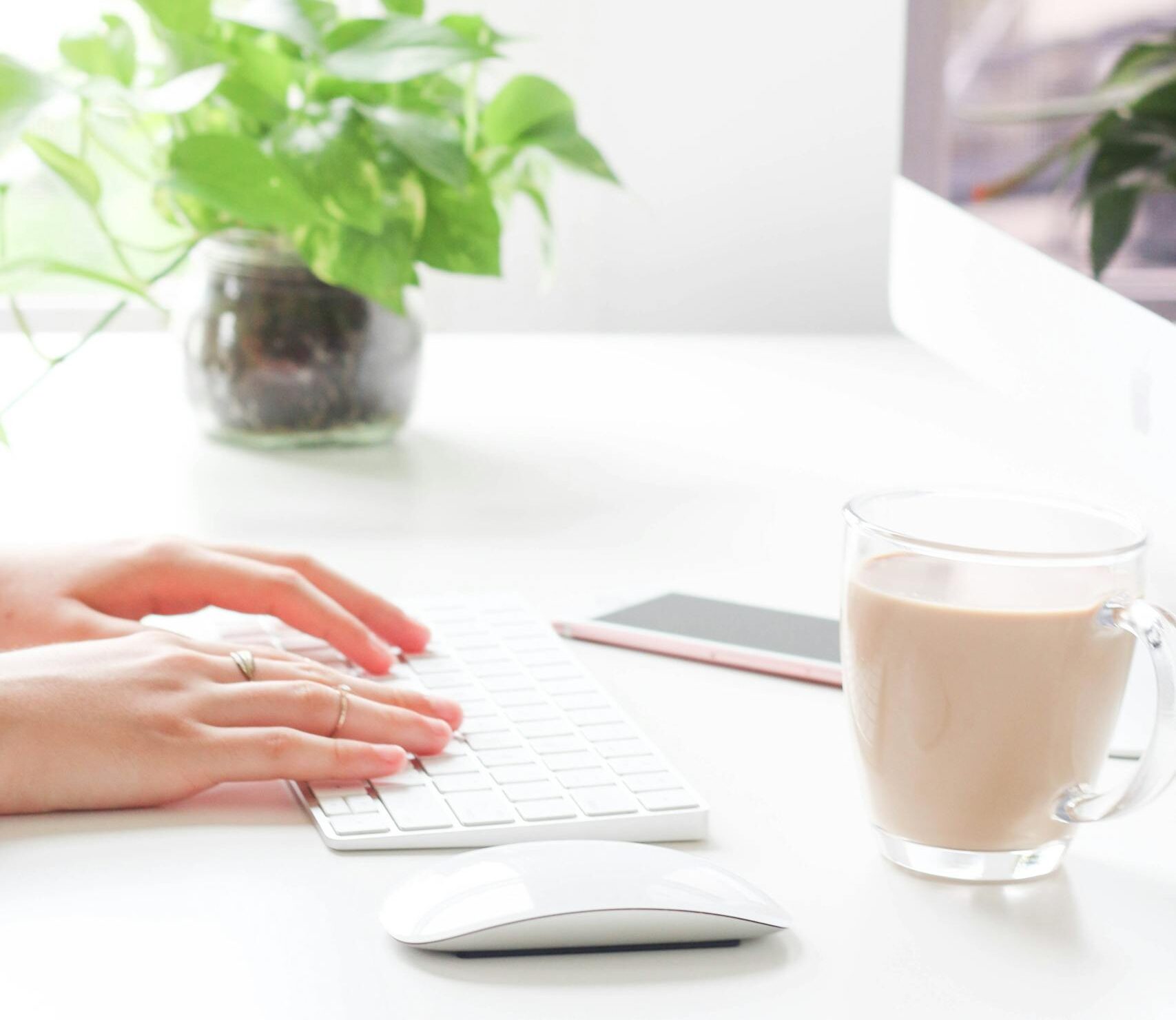 A woman working from home, typing on a keyboard with coffee nearby.
